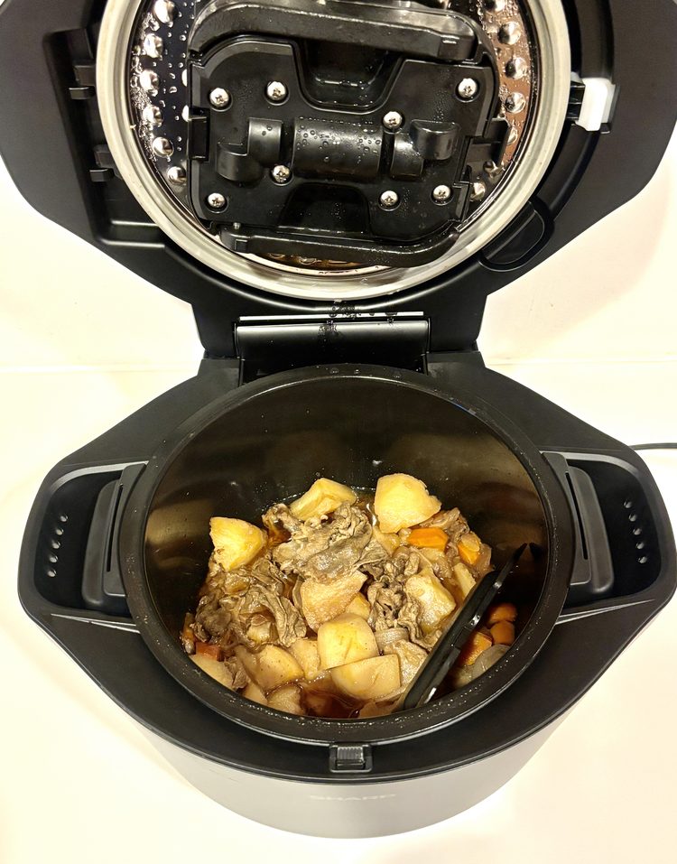 帰宅してふたを開けた瞬間の鍋の中。完成した肉じゃがの横に黒い部品が見える