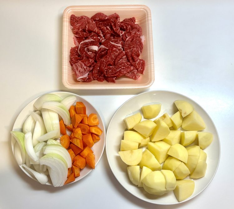 肉じゃがの材料。牛肉、くし切りの玉ねぎと乱切りのにんじん、大きめに切ったじゃがいも