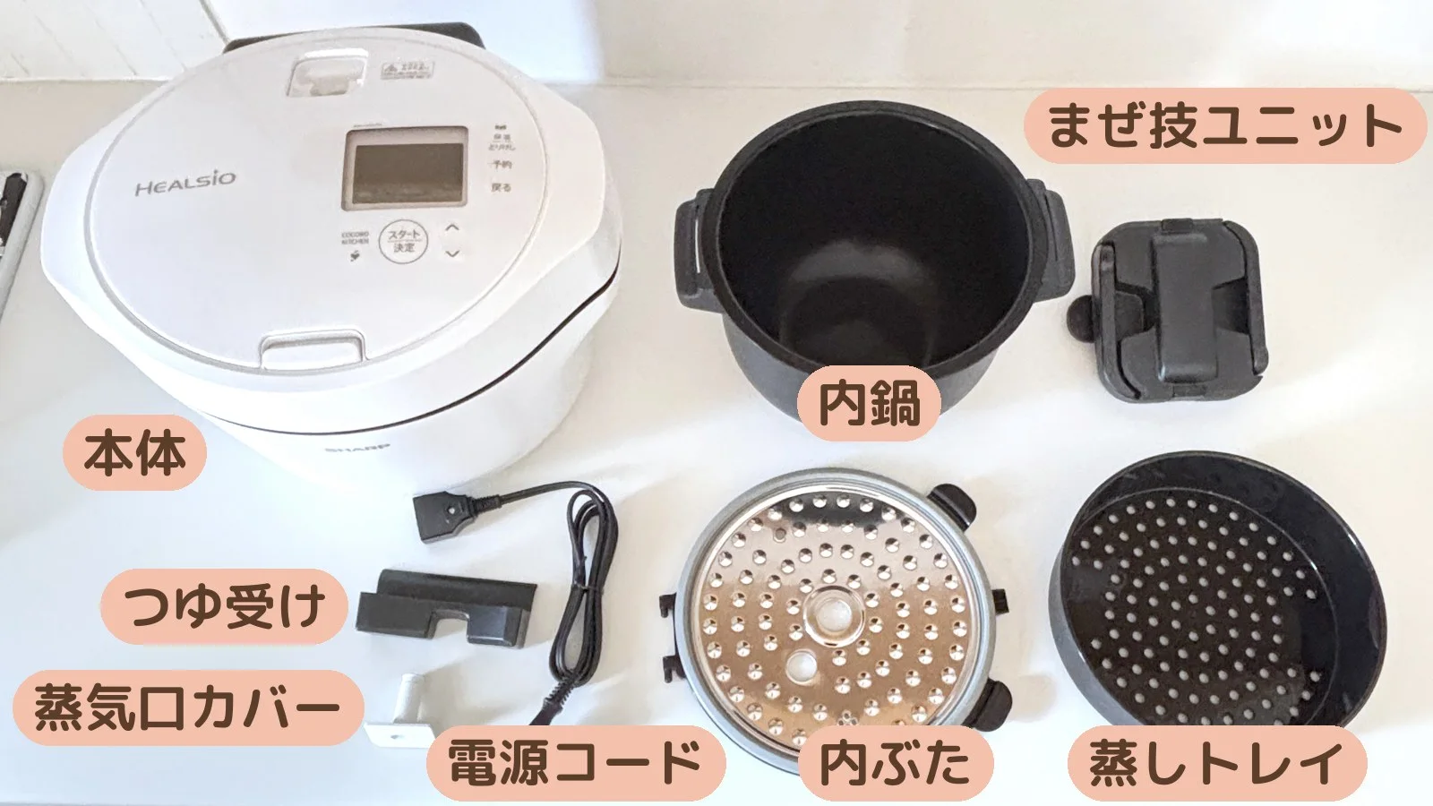 ホットクックを分解して8パーツを並べたところ。本体・内鍋・まぜ技ユニット・内ぶた・蒸しトレイ・電源コード・つゆ受け・蒸気口カバー