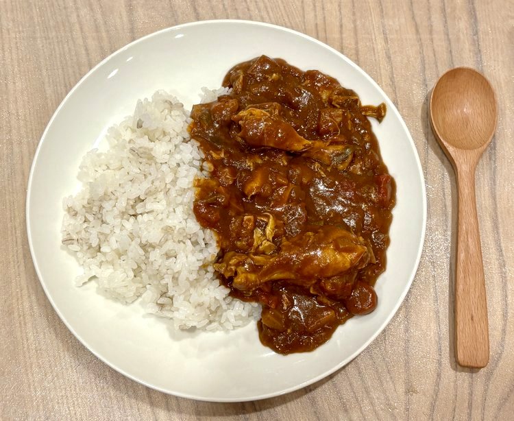 盛り付けたチキンと野菜のカレー。ごはんと赤みのあるカレー
