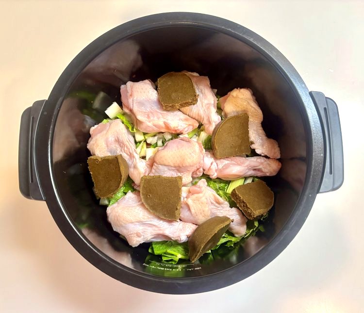 内鍋に材料を重ね入れた状態を真上から見たところ。野菜の上に手羽元とカレールウ